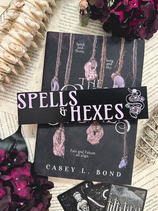 Spells & Hexes Shelf Mark™ by FireDrake Artistry® 2024. Black wooden shelf sitter with purple UV printed text that reads SPELLS & HEXES" to the left of a snake around a vile with flowers. 