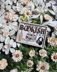 Load image into Gallery viewer, Wooden sign with a white background and tan border. Text reads "Fit Check For My Bookish Era" with flowers in the background. 
